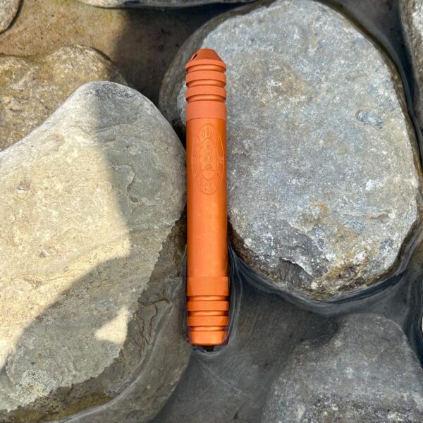 The River Tripper in Sunset Orange sitting in a pool of water among rocks keeping its contents dry