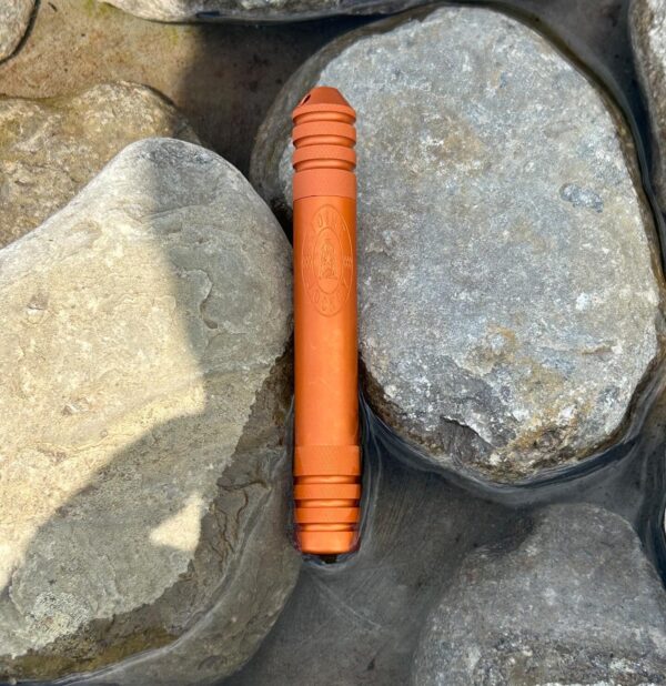 The River Tripper in Sunset Orange sitting in a pool of water among rocks keeping its contents dry